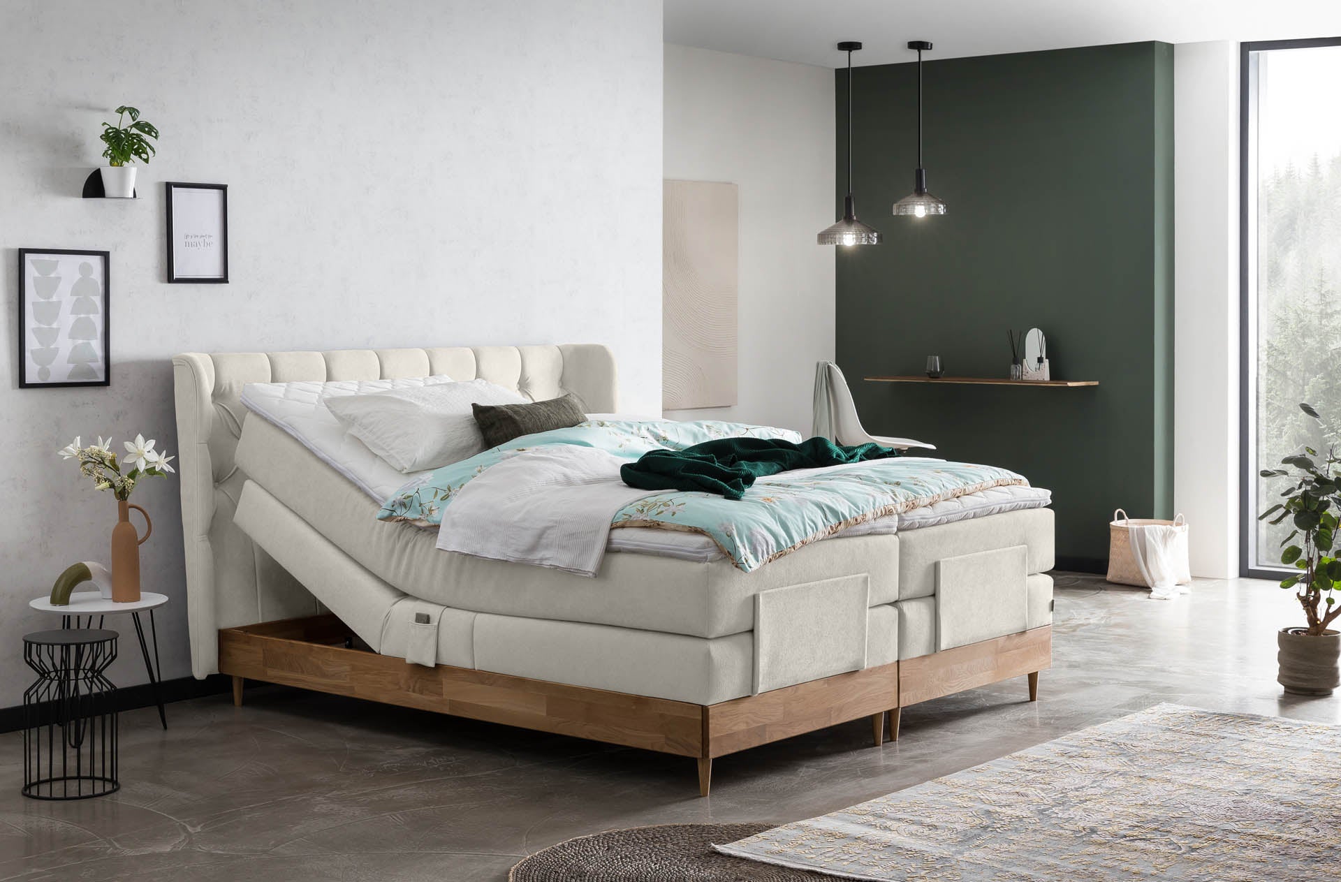 Elektrisch verstellbares Boxspringbett mit hellbeigem Stoffbezug und Holzrahmen, leicht angehobenem Kopfteil in modernem Schlafzimmer mit grüner Wand und dezenten Accessoires